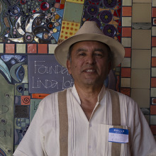 Roberto standing in front of colorful tile with a straw hat on